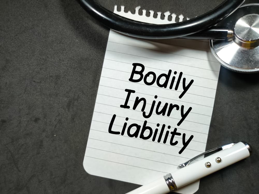 Text Bodily Injury Liability writing on notepaper with pen and stethoscope on black background.