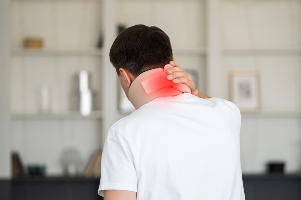 A man wearing a neck brace and cervical orthopedic bandage, illustrating the concept of health problems related to neck injuries.