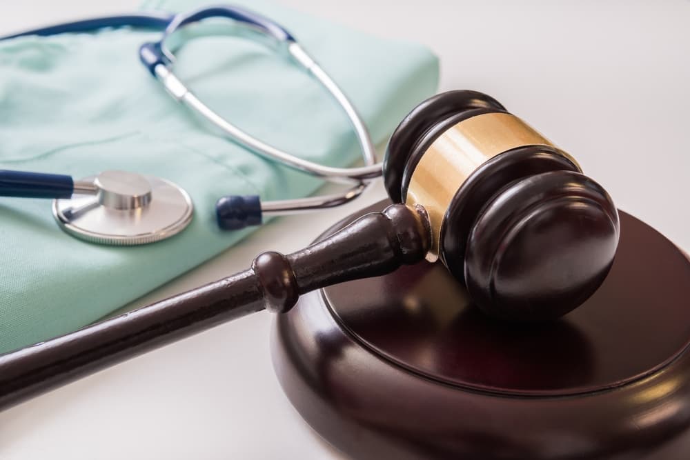 A gavel and a stethoscope are placed in the background, symbolizing the intersection of medical laws and legal concepts.